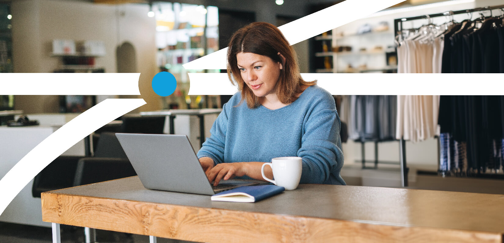 A woman seated at a table, focused on her laptop, engaged in work or study.